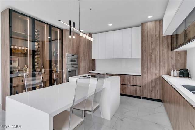 kitchen featuring a breakfast bar, white cabinets, pendant lighting, and a kitchen island