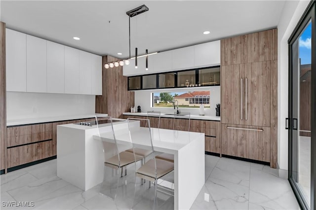 kitchen with a breakfast bar, white cabinetry, a center island, and decorative light fixtures