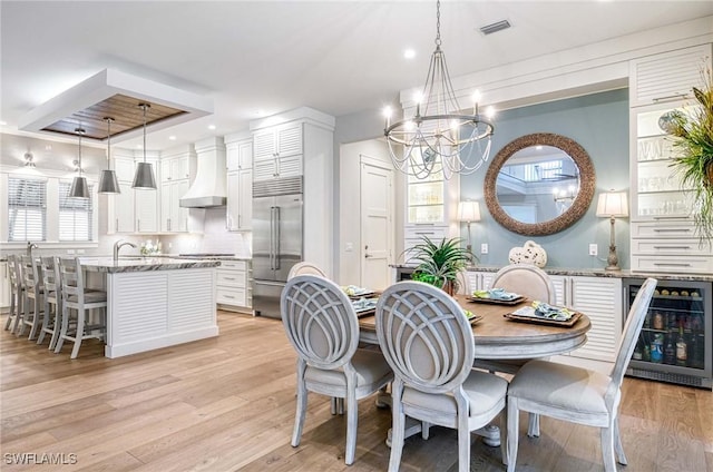 dining area featuring light hardwood / wood-style flooring, beverage cooler, and a notable chandelier