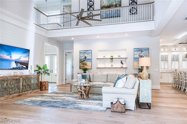 living room with ceiling fan, light hardwood / wood-style floors, and a high ceiling