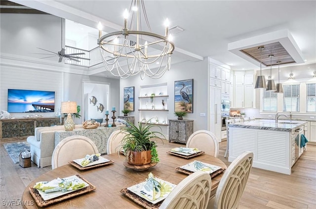 dining space featuring sink, light hardwood / wood-style floors, and ceiling fan with notable chandelier