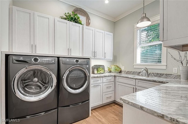 washroom with cabinets, light wood-type flooring, crown molding, sink, and independent washer and dryer