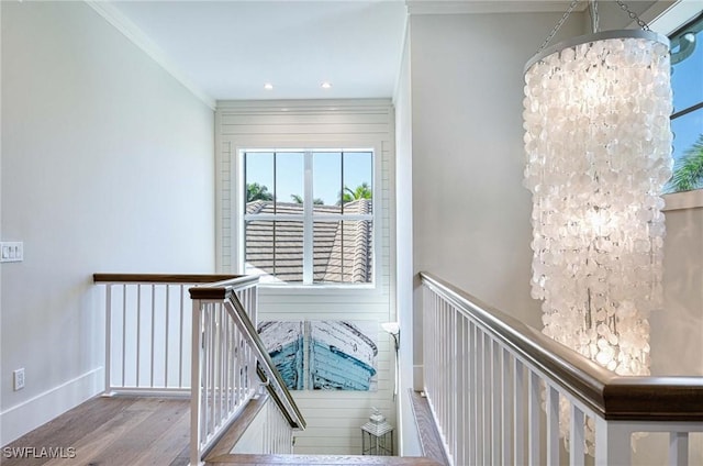 interior space featuring wood-type flooring, ornamental molding, and an inviting chandelier