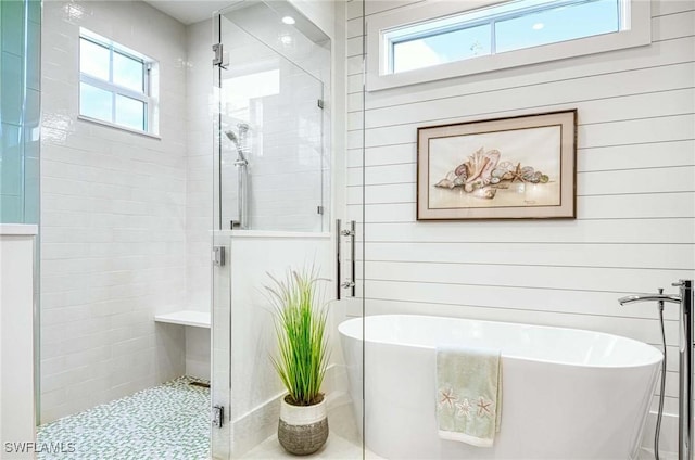 bathroom with plenty of natural light, independent shower and bath, and wood walls