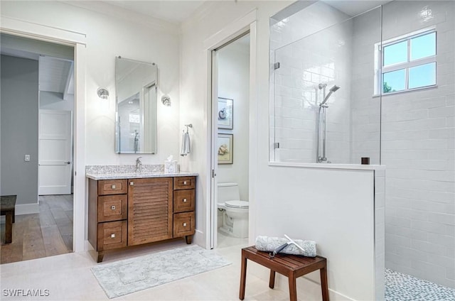 bathroom with hardwood / wood-style floors, vanity, toilet, and a tile shower