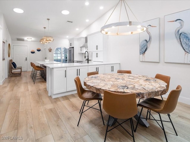 dining room featuring vaulted ceiling and light wood-type flooring