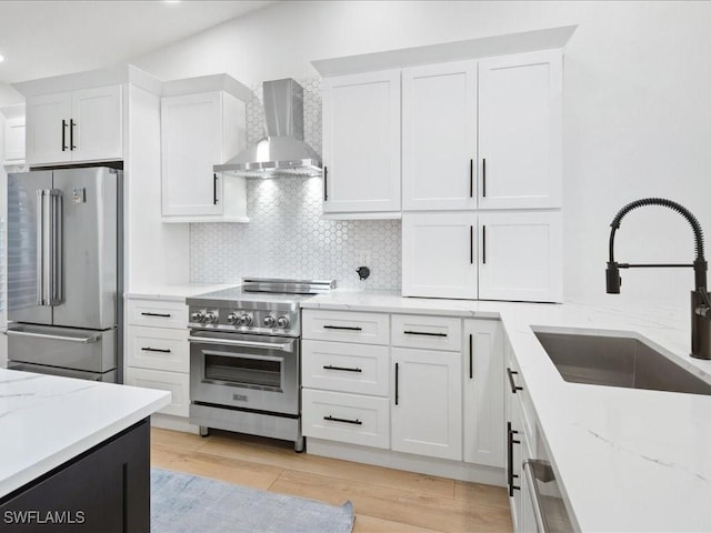 kitchen featuring white cabinets, appliances with stainless steel finishes, sink, and wall chimney range hood