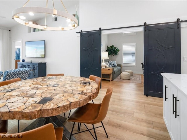 dining space featuring a barn door and light hardwood / wood-style floors