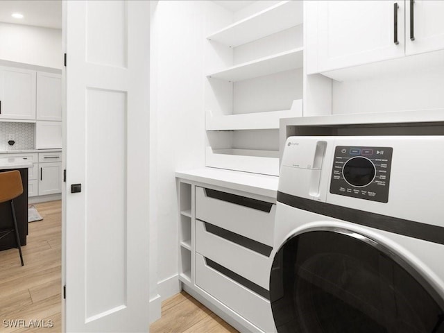 clothes washing area with light hardwood / wood-style floors, cabinets, and washer / dryer