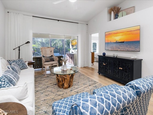 living room featuring ceiling fan, light hardwood / wood-style floors, and high vaulted ceiling