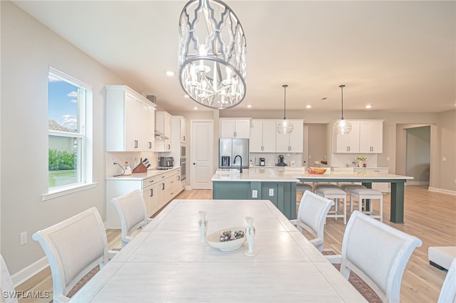 dining area with a healthy amount of sunlight, light hardwood / wood-style floors, sink, and an inviting chandelier