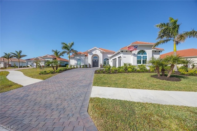 mediterranean / spanish house with a garage and a front lawn