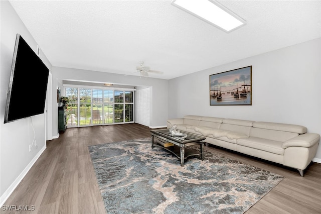 living room featuring hardwood / wood-style flooring, a textured ceiling, and ceiling fan