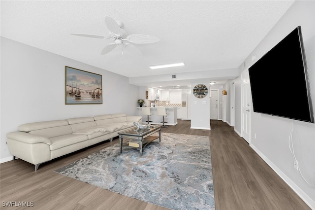 living room featuring hardwood / wood-style flooring, a textured ceiling, and ceiling fan