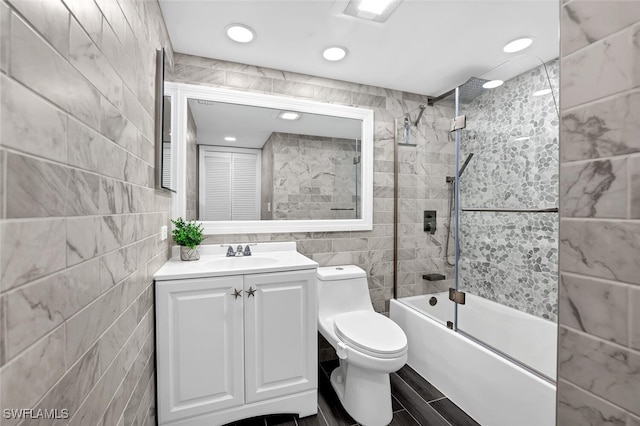 full bathroom featuring tile walls, enclosed tub / shower combo, vanity, and toilet