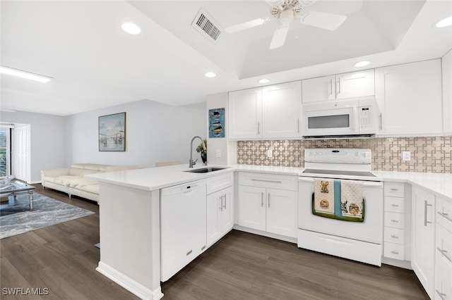 kitchen with white appliances, kitchen peninsula, dark hardwood / wood-style floors, white cabinets, and sink