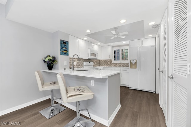 kitchen featuring sink, white cabinetry, white appliances, a kitchen breakfast bar, and kitchen peninsula