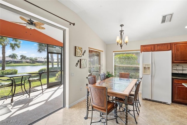 tiled dining space with ceiling fan with notable chandelier, a water view, and lofted ceiling