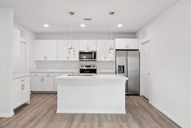 kitchen with hanging light fixtures, white cabinets, stainless steel appliances, and light wood-type flooring