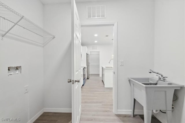 washroom with light hardwood / wood-style flooring, washer hookup, and sink