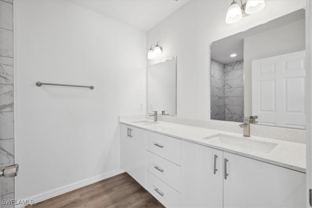 bathroom with a tile shower, vanity, and wood-type flooring