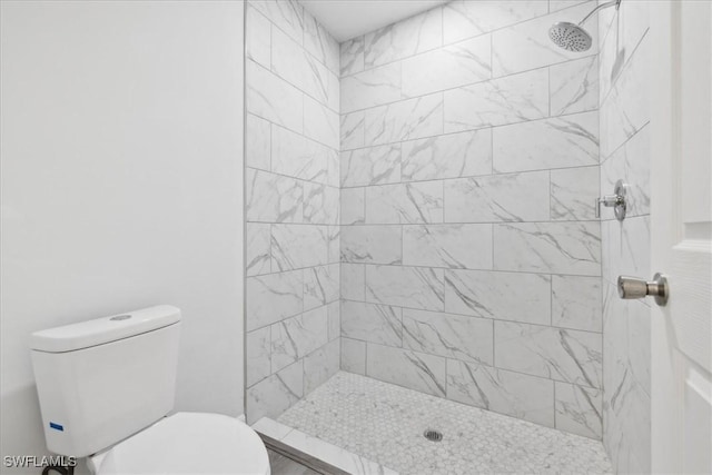 bathroom featuring tiled shower and toilet