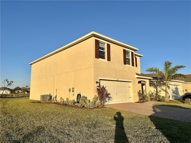 view of home's exterior with central air condition unit, a garage, and a lawn