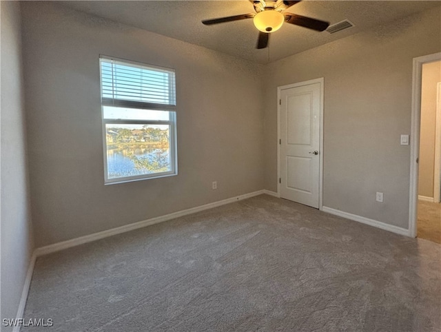 empty room with carpet flooring, ceiling fan, and a textured ceiling