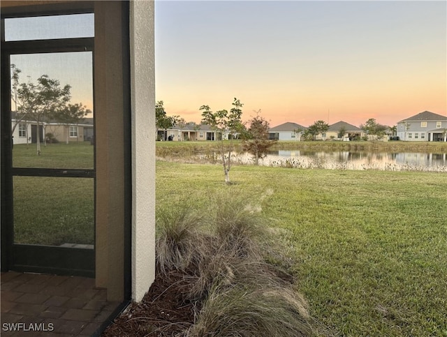 yard at dusk featuring a water view