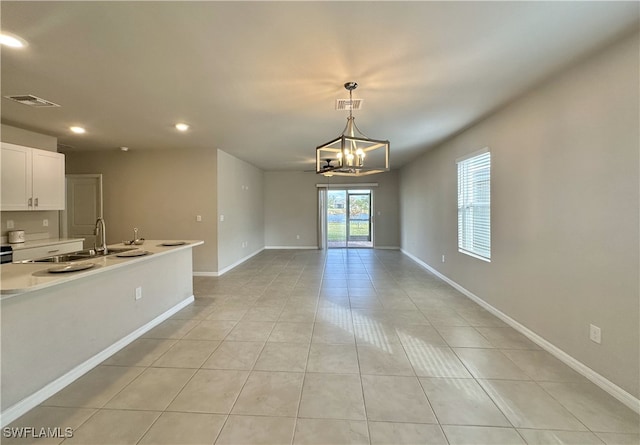 interior space featuring white cabinetry, sink, a notable chandelier, decorative light fixtures, and light tile patterned floors