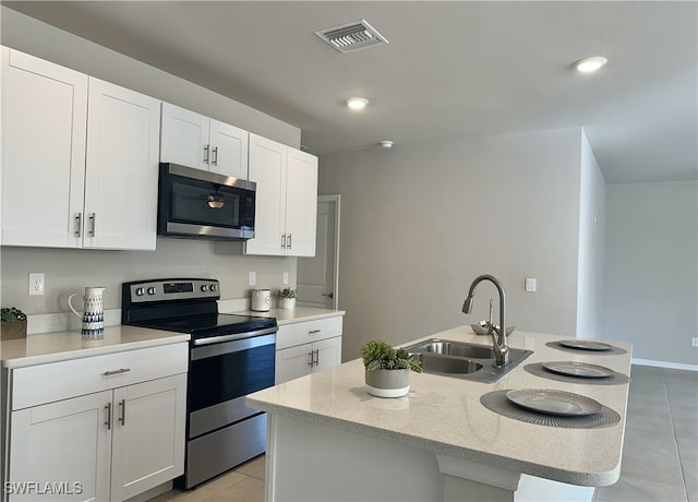 kitchen with white cabinets, sink, stainless steel appliances, and an island with sink