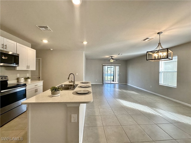 kitchen featuring stainless steel appliances, sink, decorative light fixtures, a center island with sink, and white cabinets