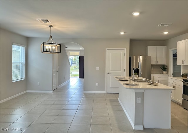 kitchen with a kitchen island with sink, white cabinets, sink, hanging light fixtures, and stainless steel appliances