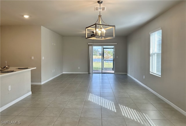 spare room featuring a chandelier and light tile patterned floors