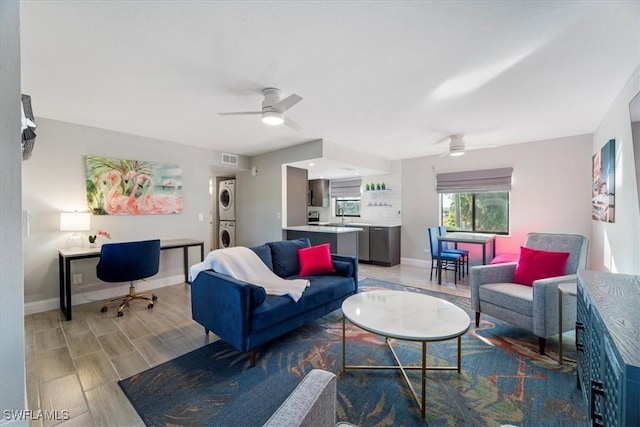 living room featuring stacked washer / drying machine and ceiling fan