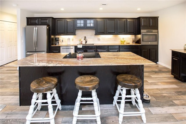 kitchen with sink, stainless steel appliances, a kitchen breakfast bar, and a kitchen island with sink