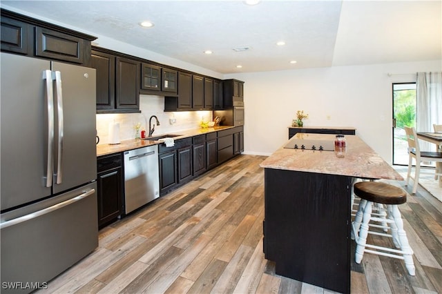 kitchen with decorative backsplash, light hardwood / wood-style flooring, stainless steel appliances, and a kitchen island