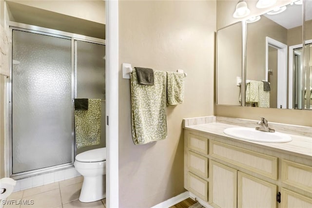 bathroom with tile patterned floors, vanity, a shower with shower door, and toilet