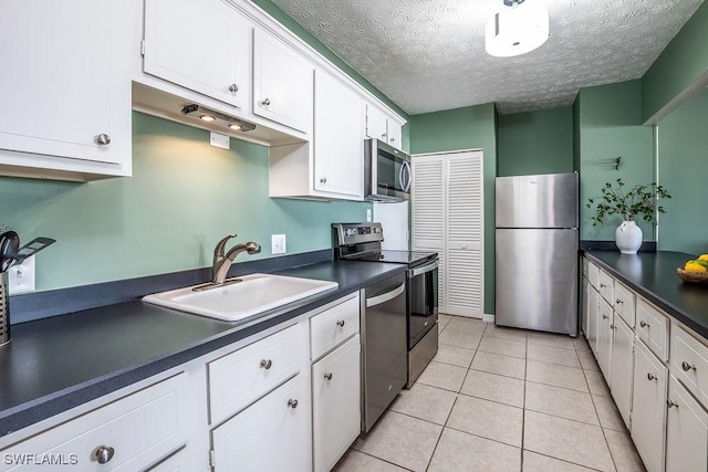 kitchen featuring stainless steel appliances, light tile patterned flooring, sink, and white cabinets