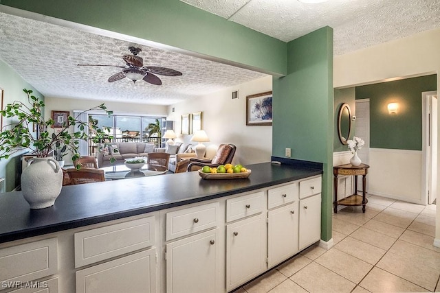 kitchen with ceiling fan, white cabinets, light tile patterned flooring, and a textured ceiling