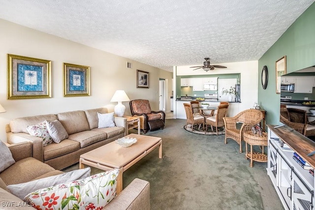 carpeted living room with ceiling fan and a textured ceiling