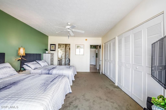 carpeted bedroom featuring two closets, ceiling fan, and a textured ceiling