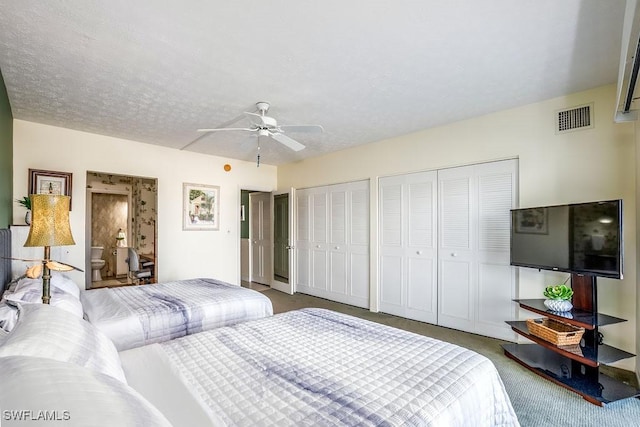 carpeted bedroom with ceiling fan, a textured ceiling, and multiple closets