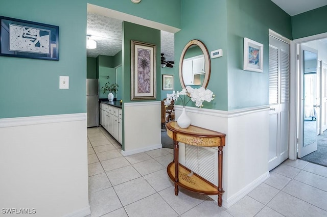 hallway with a textured ceiling and light tile patterned flooring