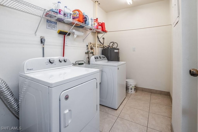 laundry room featuring water heater, light tile patterned floors, and independent washer and dryer