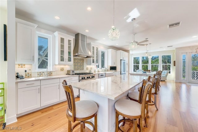 kitchen with white cabinetry, wall chimney range hood, tasteful backsplash, pendant lighting, and a kitchen island