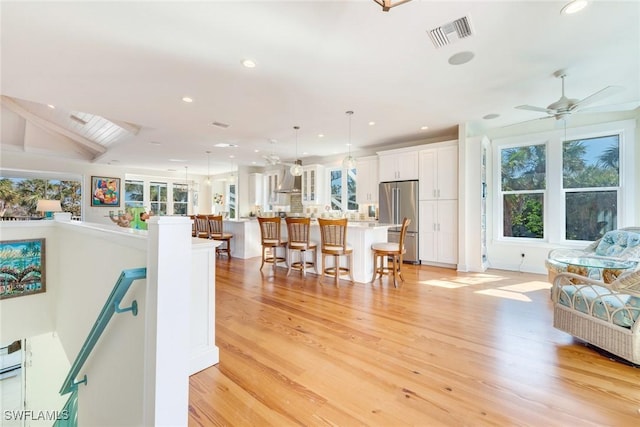 living room with vaulted ceiling, light hardwood / wood-style flooring, and ceiling fan