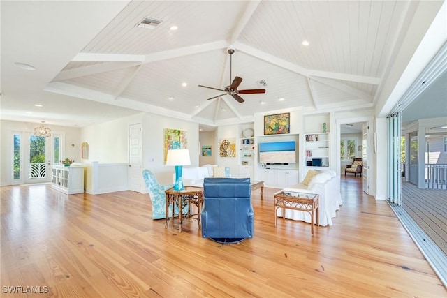 living room featuring vaulted ceiling with beams, plenty of natural light, ceiling fan with notable chandelier, and light hardwood / wood-style flooring