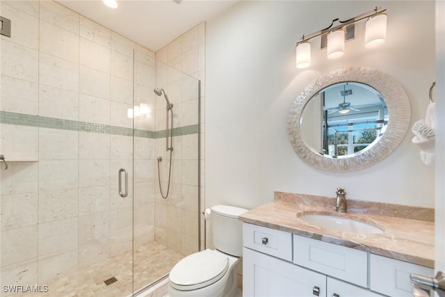 bathroom featuring vanity, toilet, ceiling fan, and a shower with shower door