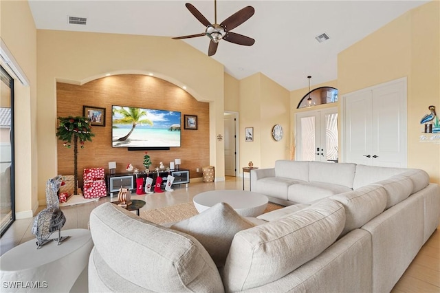 living room featuring ceiling fan, french doors, light tile patterned flooring, wooden walls, and lofted ceiling